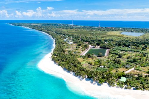 Free A scenic aerial view of a tropical island with turquoise waters and lush vegetation. Stock Photo