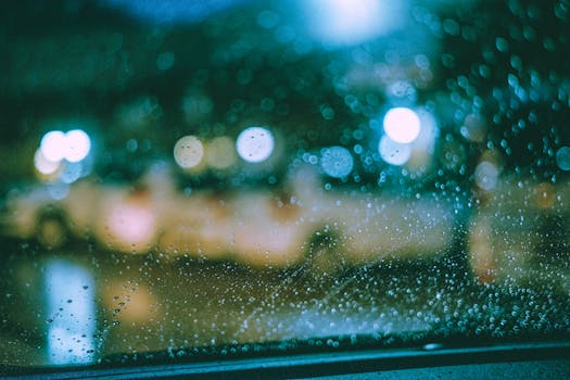 Bokeh effect of city lights through a rain-drenched window captures a moody night atmosphere.