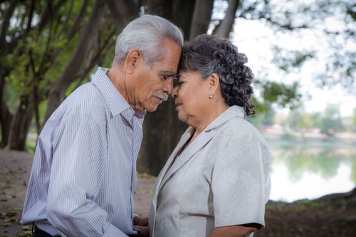 Free An elderly couple lovingly embraces with heads touching in a serene outdoor setting. Stock Photo