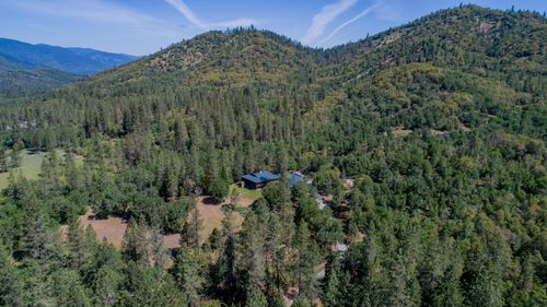 Free A stunning aerial view of a lush green forested mountain landscape under a clear blue sky. Stock Photo