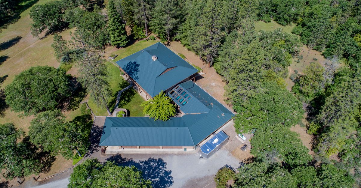 Aerial view of a secluded house surrounded by lush green forest and foliage.