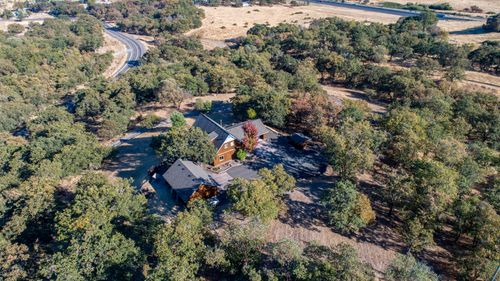 Free Aerial view showcasing a house surrounded by lush green trees in a scenic landscape. Stock Photo