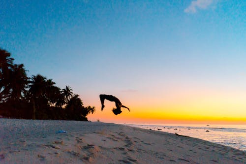 Man Backflipping on Beach during Sunset
