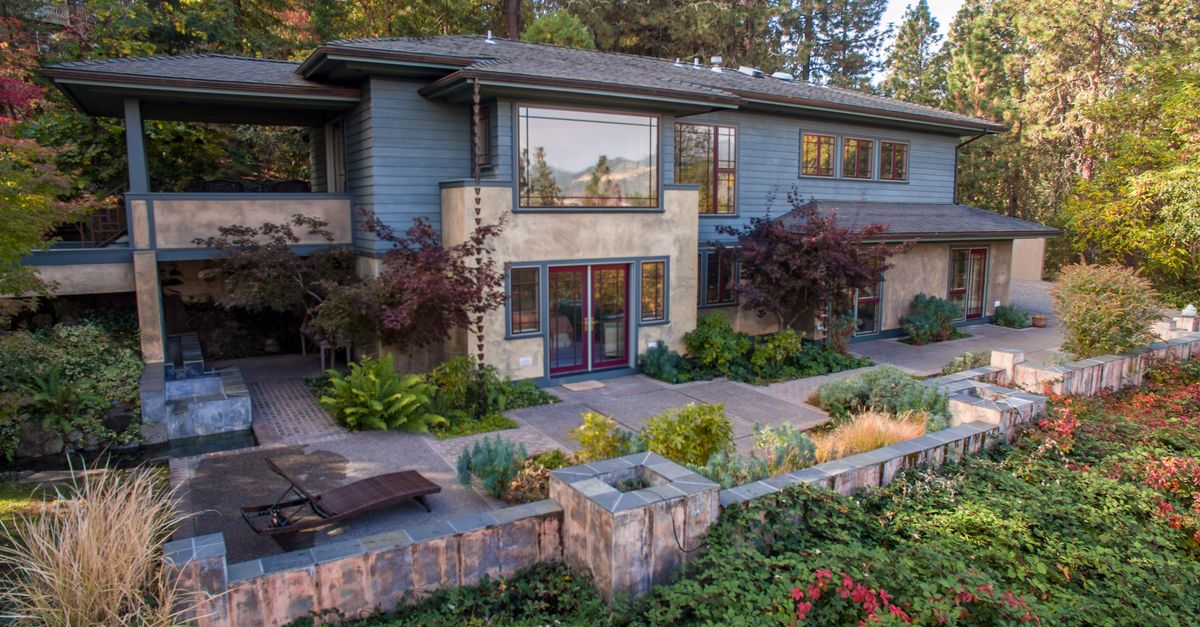 Contemporary two-story house surrounded by a lush garden, showcasing a stunning facade.