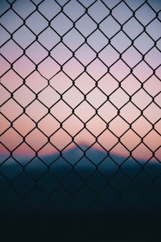 Metal grid barrier located in countryside on sunset with mountainous landscape on background