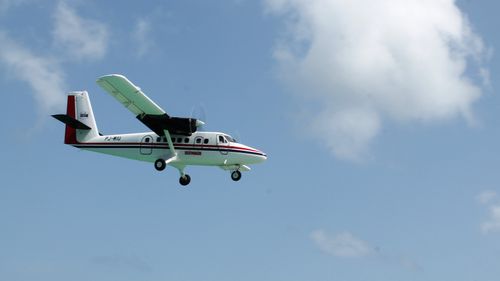 Free A Twin Otter airplane captured flying high in the clear sky over Sint Maarten. Stock Photo