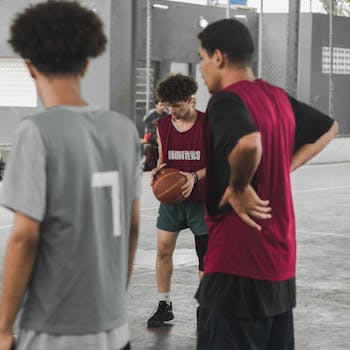 A group of teenagers playing basketball indoors, focusing on a player holding the ball during practice.