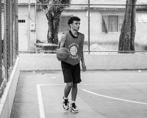 Free Black and white image of a young man playing basketball outdoors, wearing a sports jersey. Stock Photo