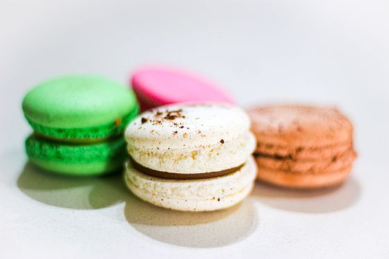 Green, pink, white and tan macarons with a chocolate-filled vanilla macaron in front