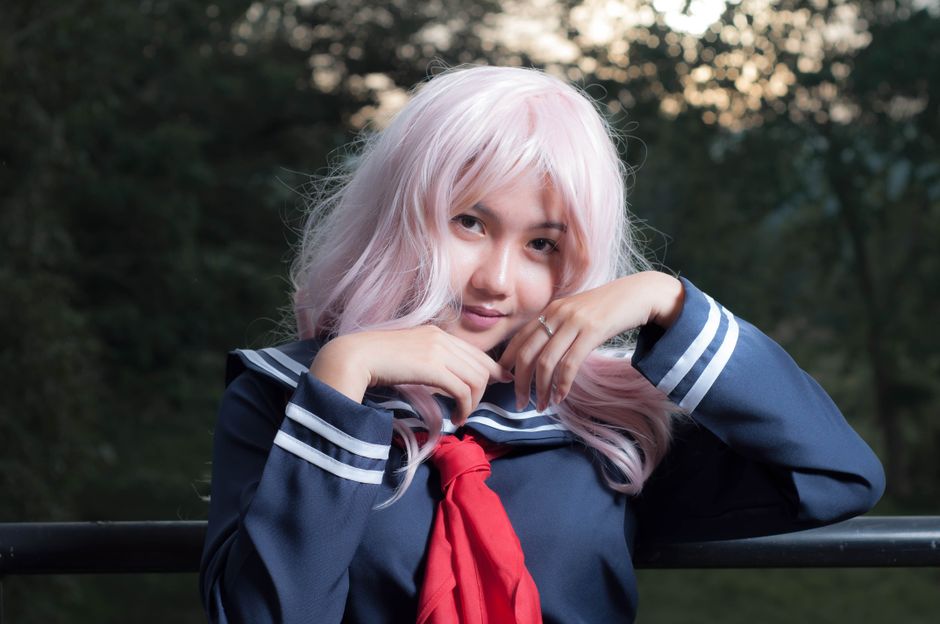 Beautiful Asian woman posing outdoors in a sailor outfit with pink hair.