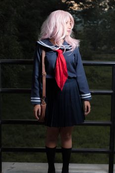 一位粉红色头发的优雅女子在户外穿着水手校服摆姿势