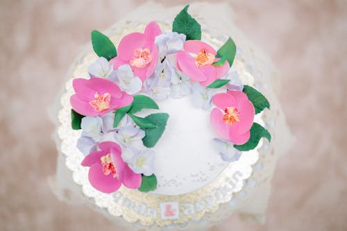 Top view of fresh wedding cake decorated with flowers and leaves on golden plate