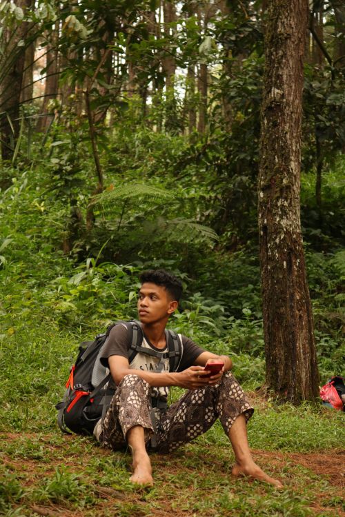 Free A young man sits barefoot in a vibrant West Java forest, enjoying nature's tranquility. Stock Photo