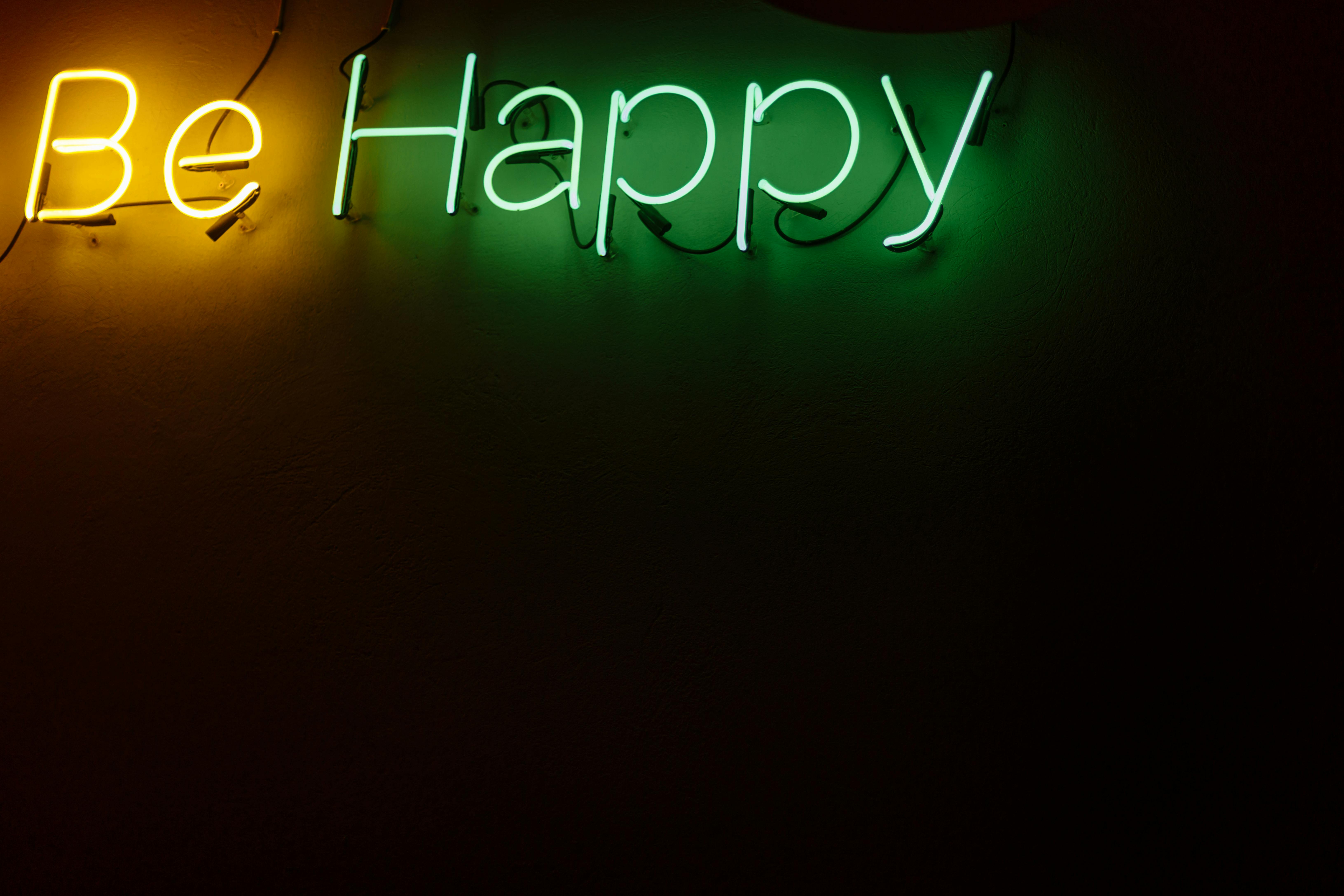 Bright neon sign reading 'Be Happy' on a dark background. Ideal for motivational themes.