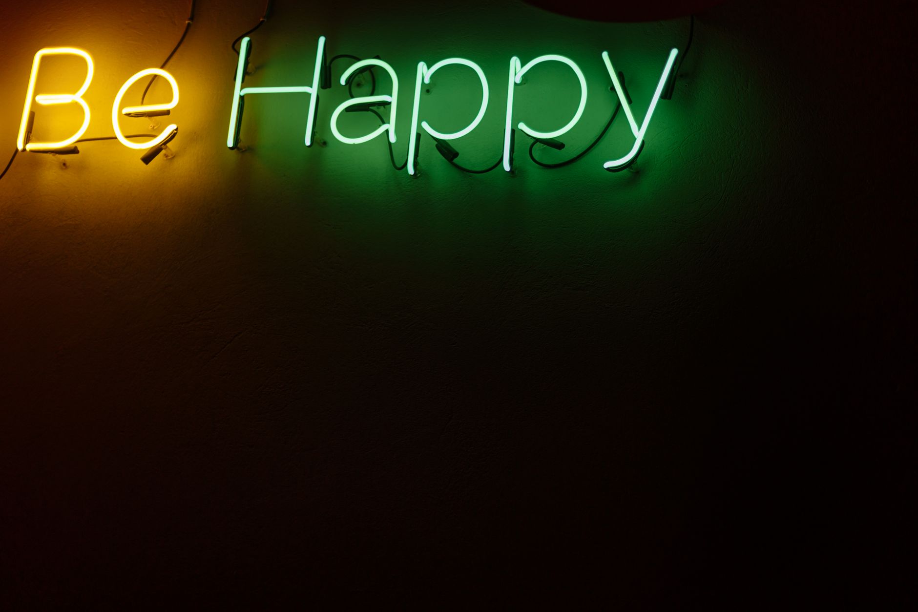 Bright neon sign reading 'Be Happy' on a dark background. Ideal for motivational themes.