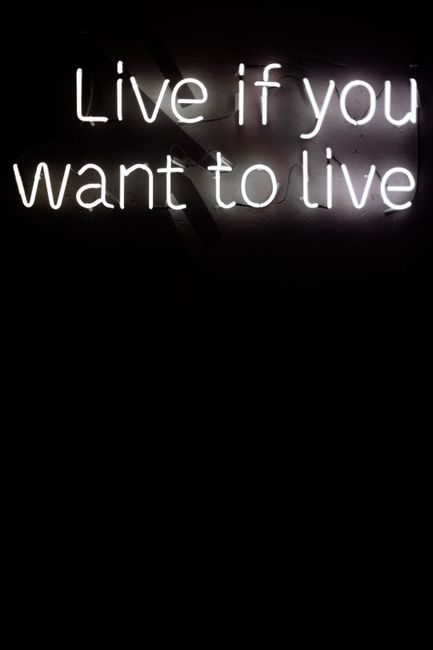 Illuminated neon sign with empowering quote on a dark background.
