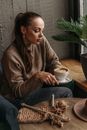 穿着毛衣的女人在室内一边编织一边喝咖啡，营造出舒适的氛围