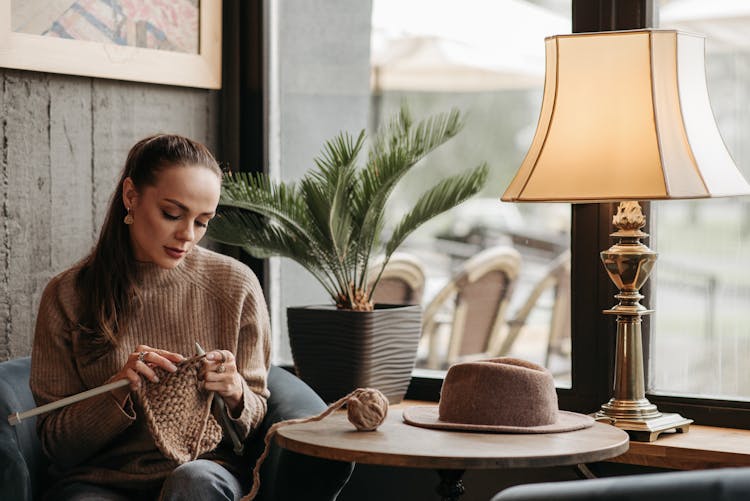 Woman In Sweater Knitting Beside A Window