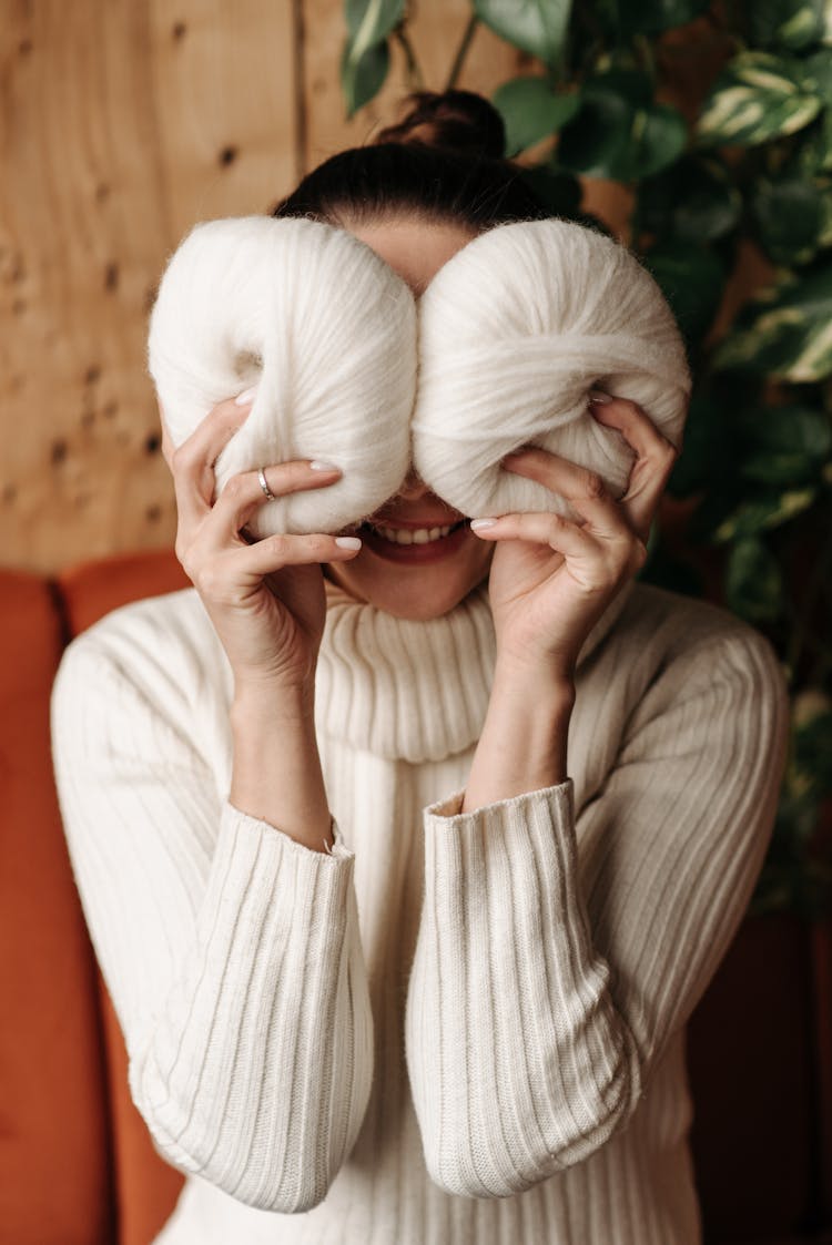 Woman In White Sweater Holding Yarn Rolls