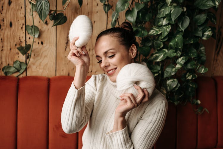 Woman In Turtle Neck Sweater Holding Yarn Rolls