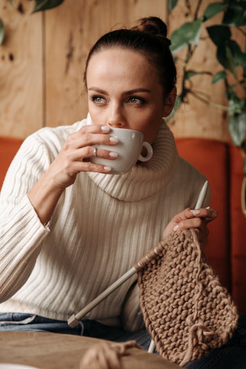 Free Woman Drinking Coffee and Holding a Crochet Stock Photo