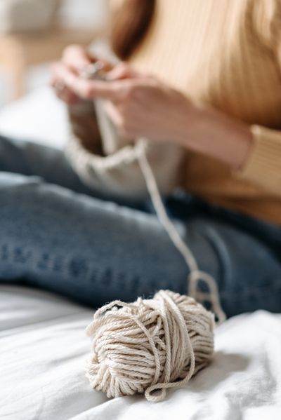 Winding a ball of ecru yarn while seated — Pavel Danilyuk on Pexels