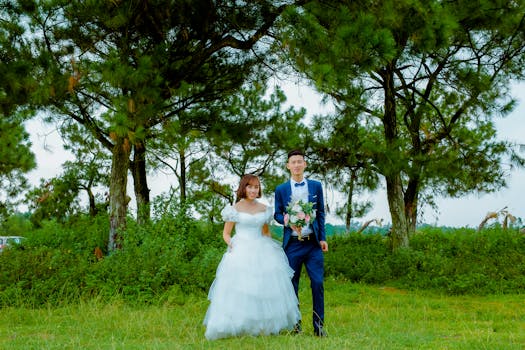 Bride and groom posing in a lush green park setting, capturing a joyful summer wedding moment.