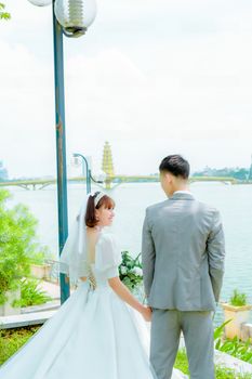 Bride and groom in a serene outdoor setting by the lake, back view.