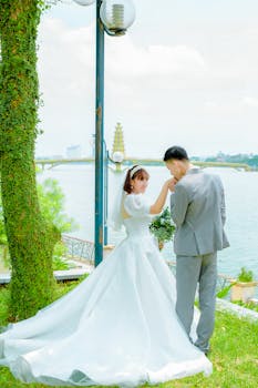 Bride and groom share a tender moment in a beautiful outdoor lakeside setting.