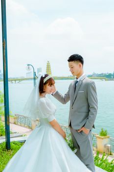 Beautiful bride and groom share a tender moment by the water, celebrating love and togetherness.