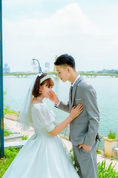 A romantic wedding moment between a bride and groom by the waterfront.