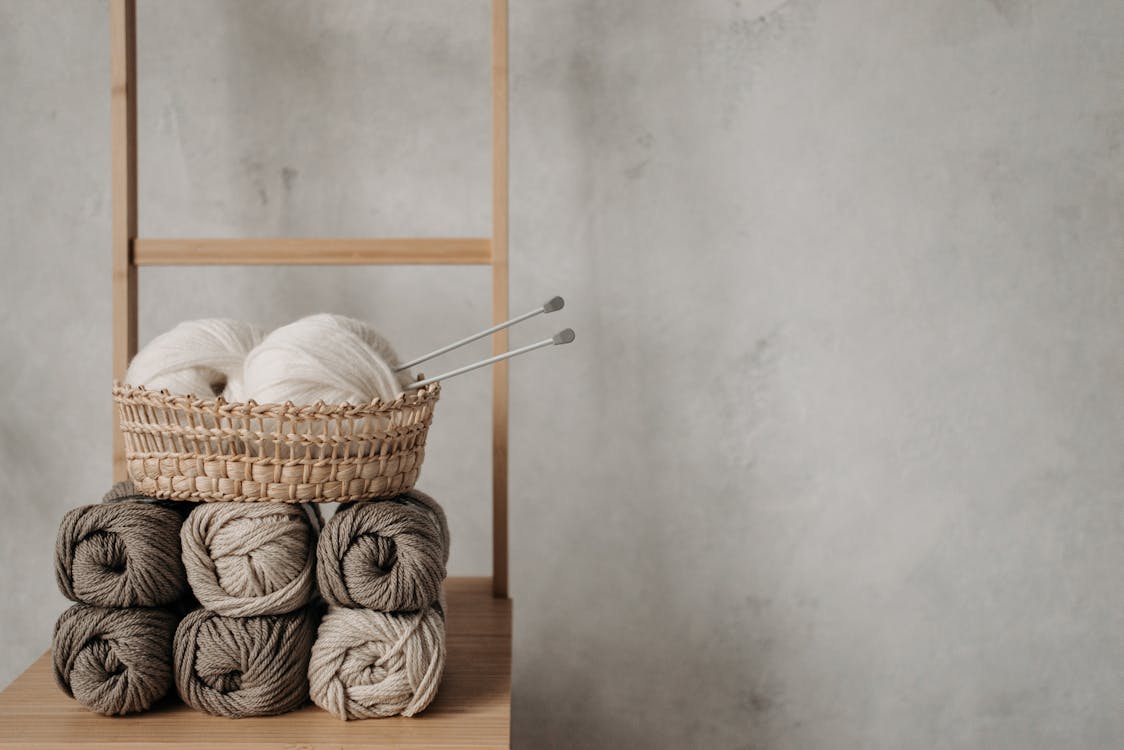 Woven Basket With Yarn Rolls on Brown Wooden Table