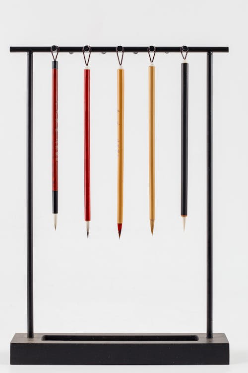 Free Collection of bright modern Japanese calligraphy brushes hanging on pen rack on white background Stock Photo