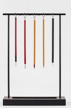 Collection of bright modern Japanese calligraphy brushes hanging on pen rack on white background