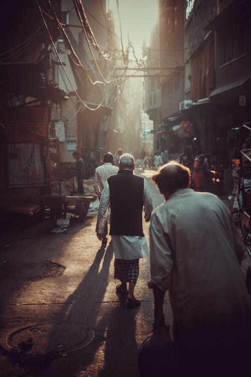 Back View of People Walking on a Narrow Alley