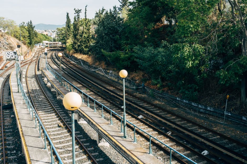 Curved railway tracks with metal railings and trees along the path.