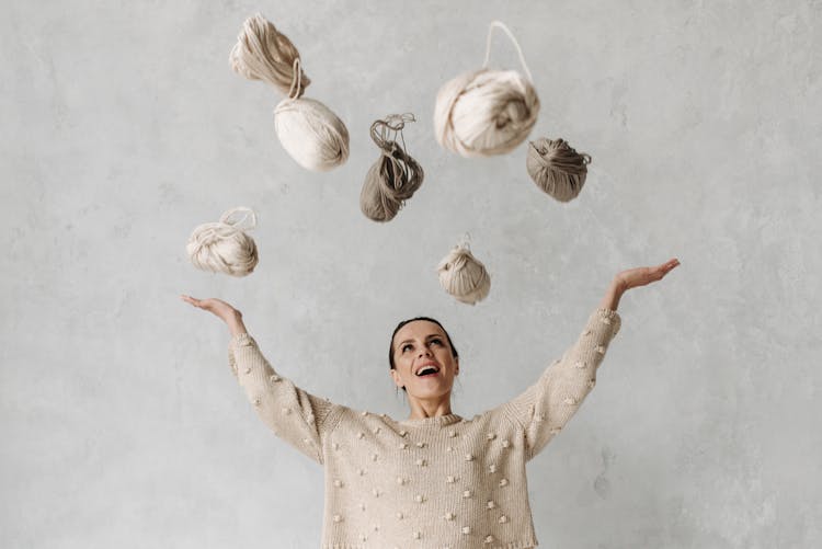 A Woman In A Sweater Throwing Yarns