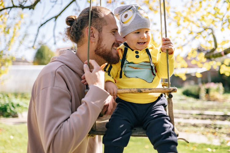 Smiling Toddler Sitting On A Swing