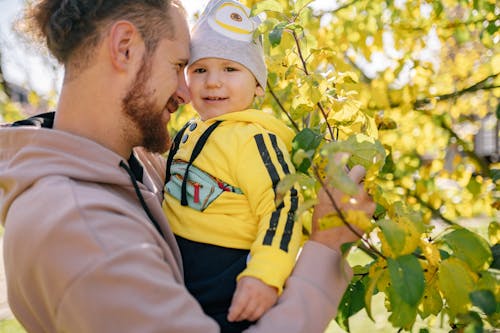 A Man in Brown Long Sleeves Holding a Baby