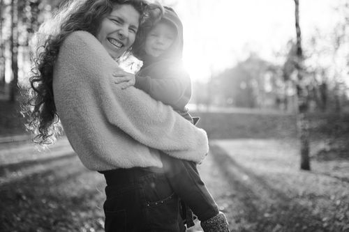 Free Black and white photo of a happy mother holding her child in sunlight. Stock Photo