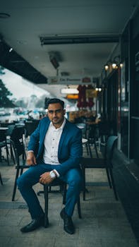Professional man in a blue suit sitting at an outdoor cafe, exuding confidence.