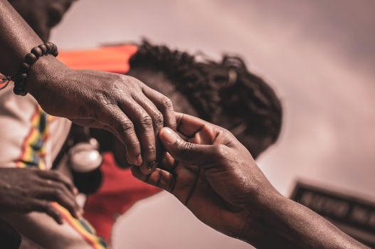 Detailed close-up of hands interacting outdoors, with a blurred background suggesting connection.