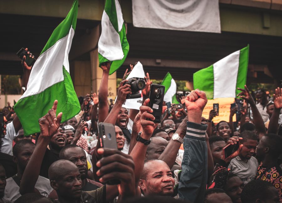 A lively street protest in Nigeria with activists waving flags and holding signs.