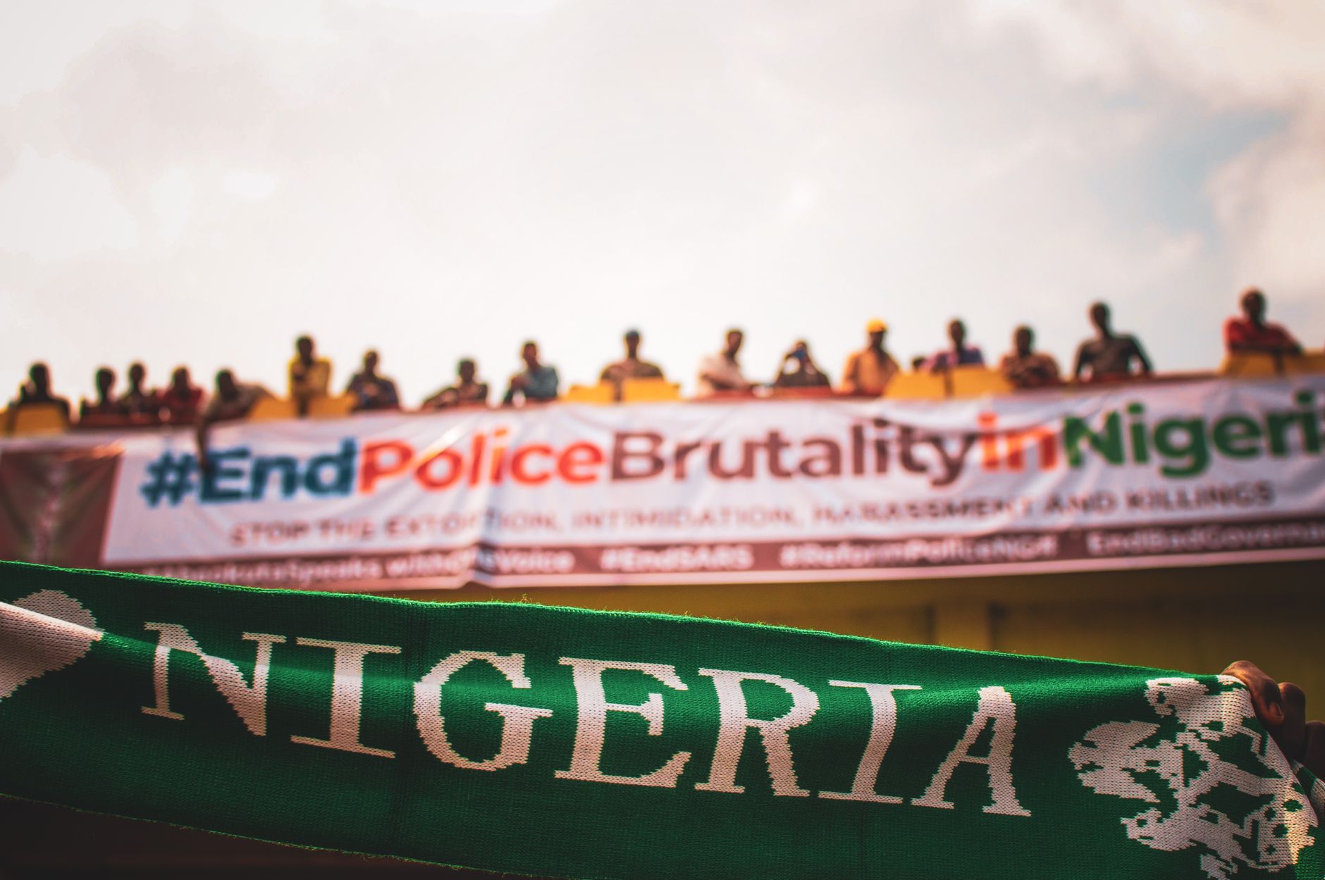 Mass protest demanding an end to police brutality in Nigeria, featuring a large banner.