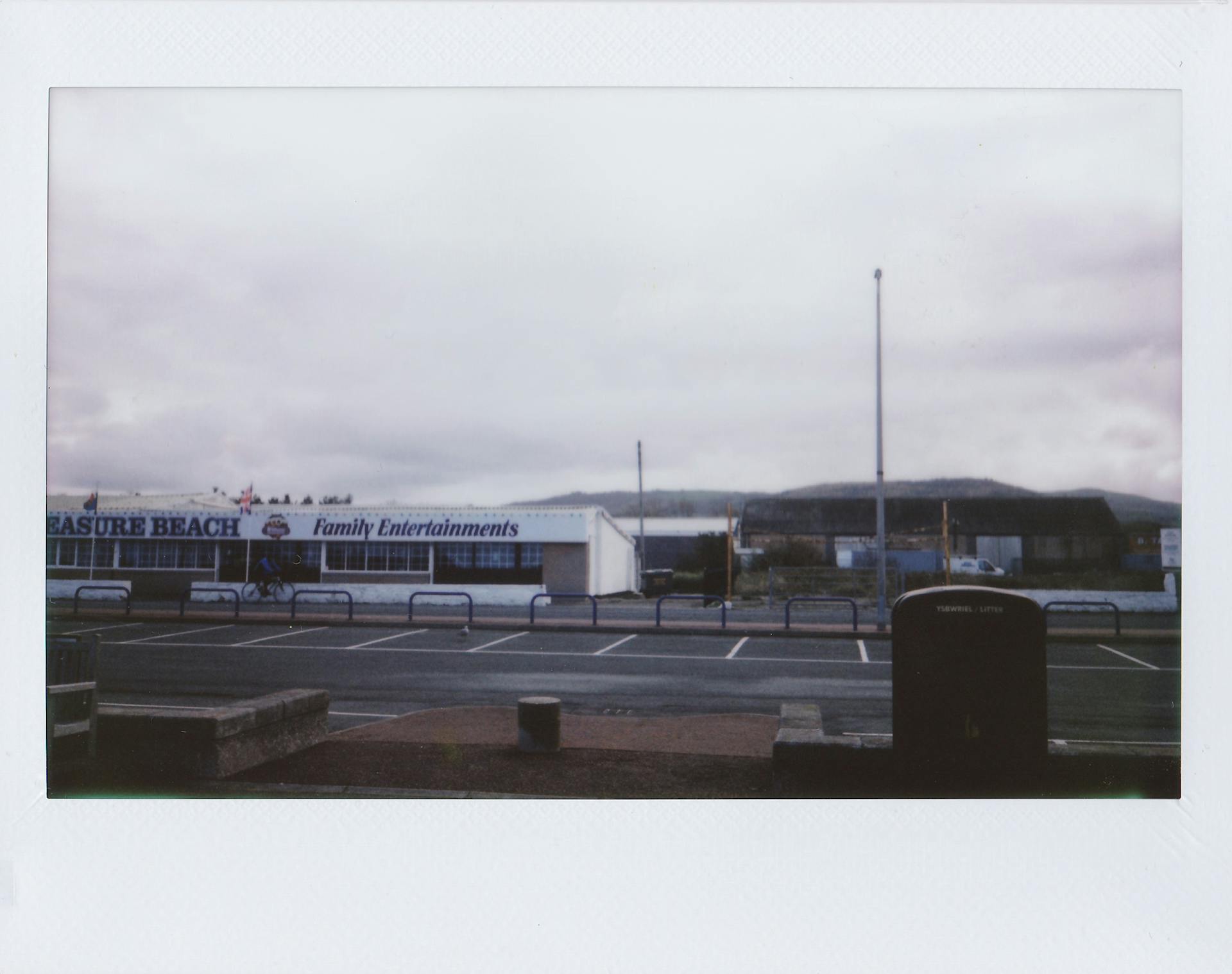 An empty parking lot near a family entertainment center under an overcast sky, outdoor urban setting.