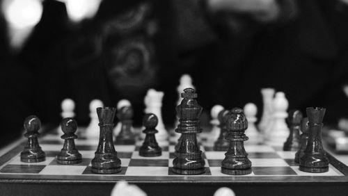 Free Black and white of wooden chess pieces placed on chessboard placed in dark room against blurred background Stock Photo