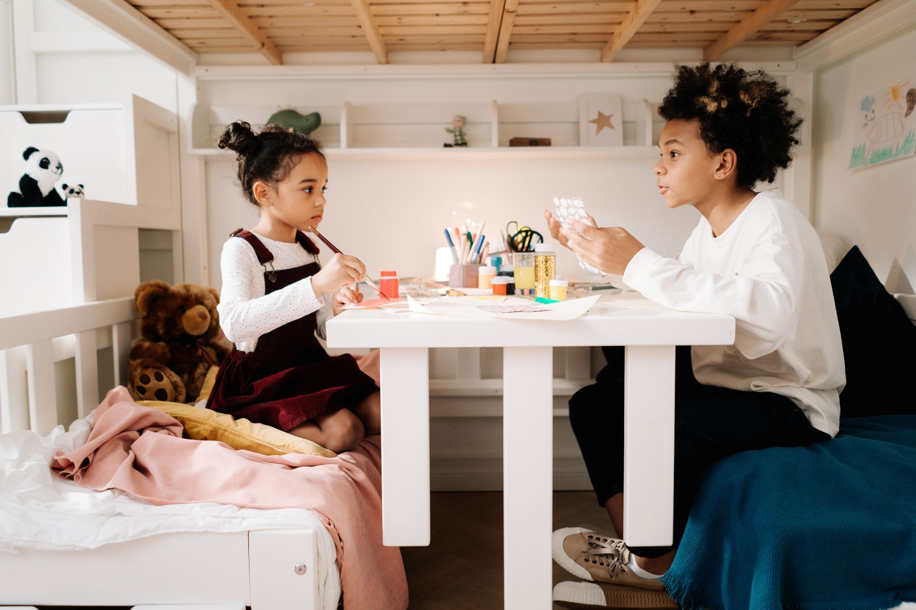 Two children crafting together in a cozy bedroom. Creative play enhances sibling bonding and imagination.