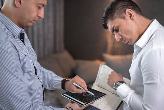Two professionals engaged in a business meeting using a digital tablet and handwritten notes.