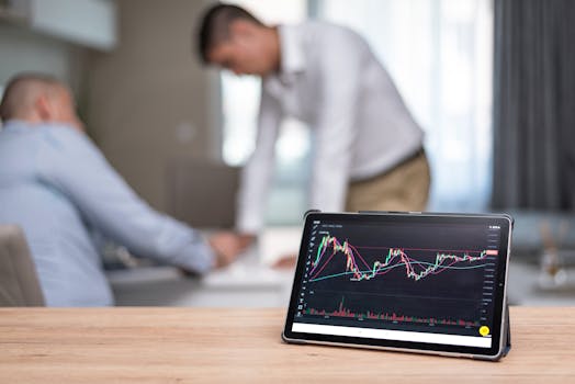 Tablet displaying stock market chart during professional meeting with two men in discussion.
