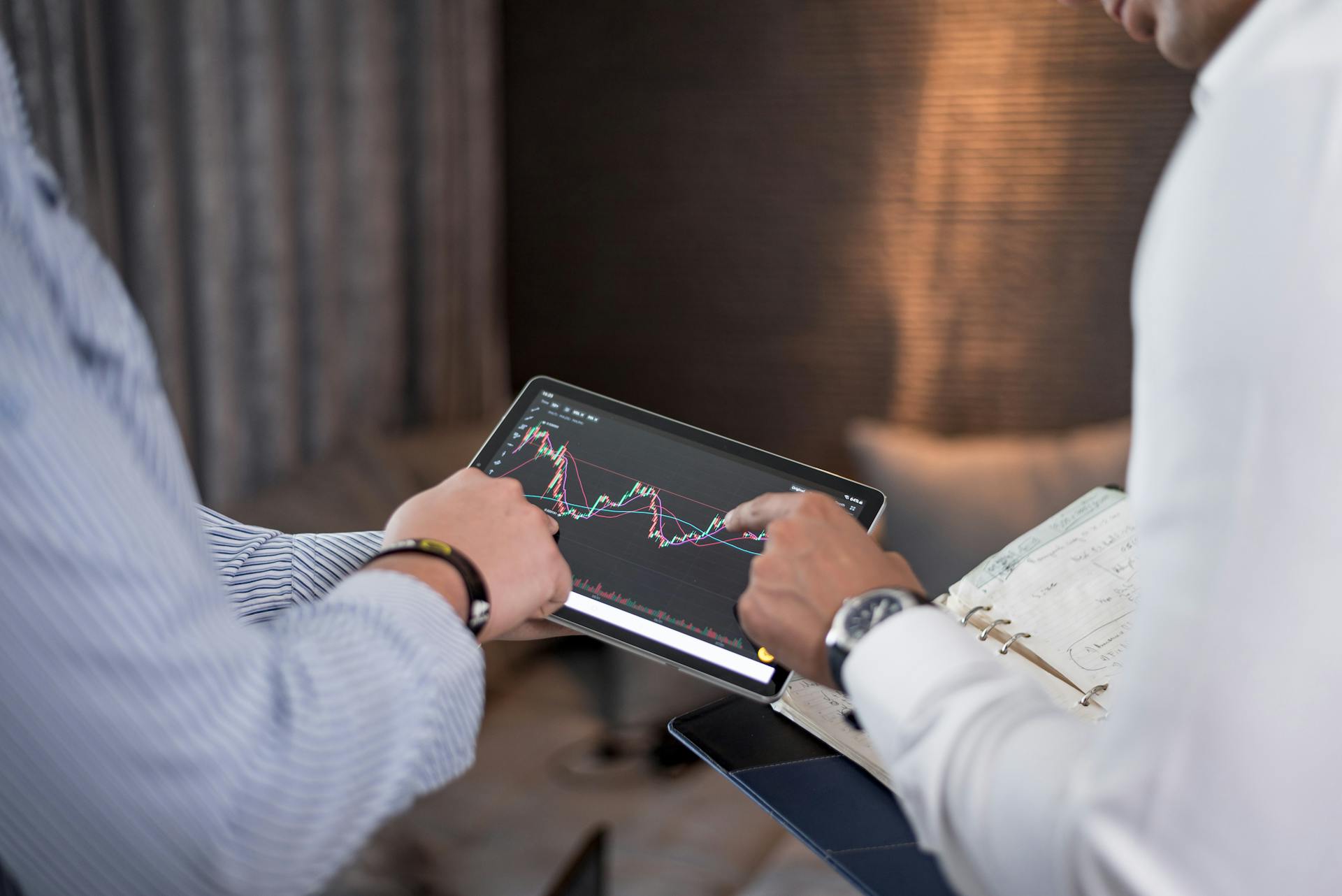 Close-up of business professionals discussing financial data on a digital tablet.